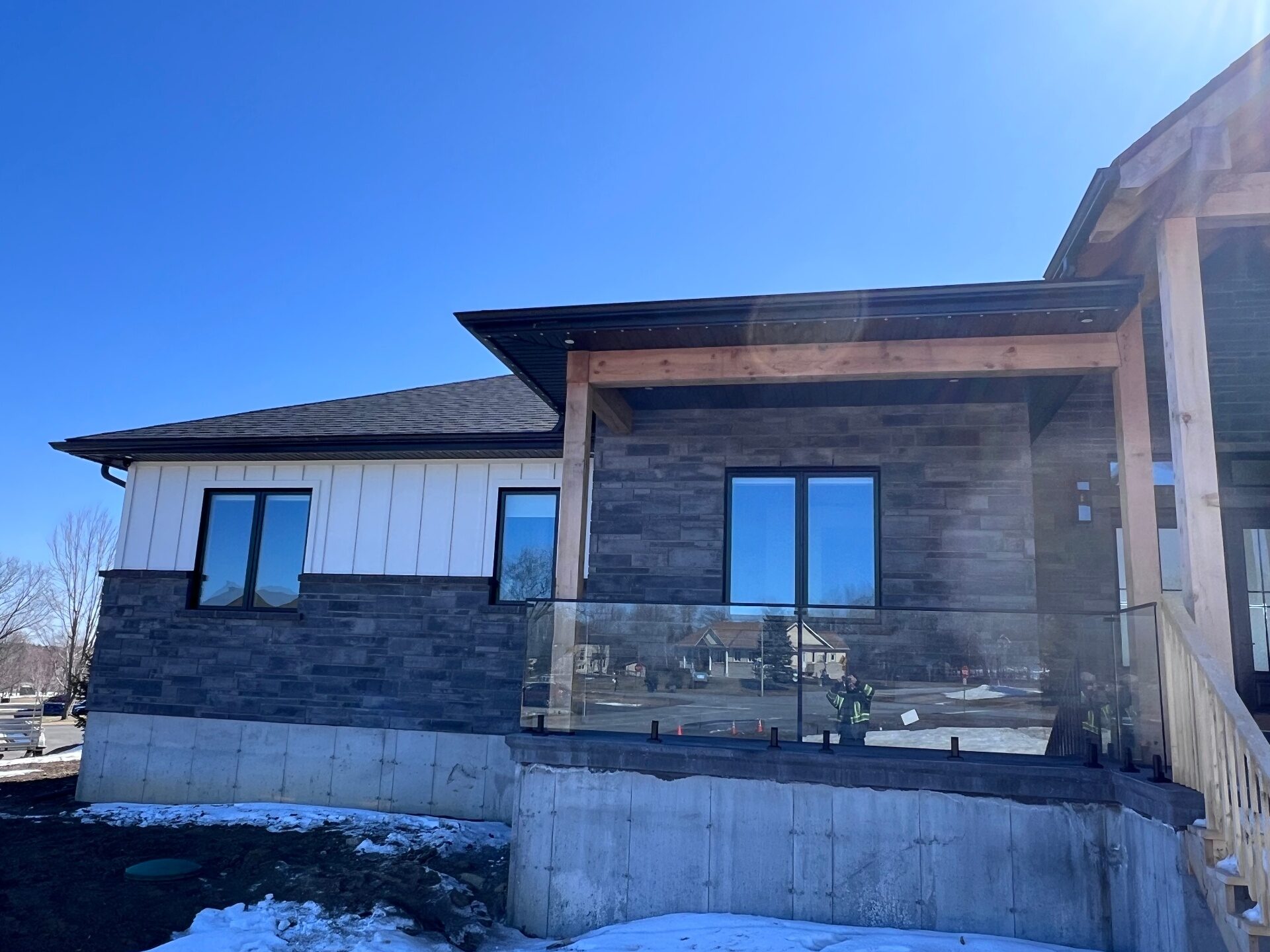 Custom black aluminum eavestrough on a Kanata home with stone and white siding